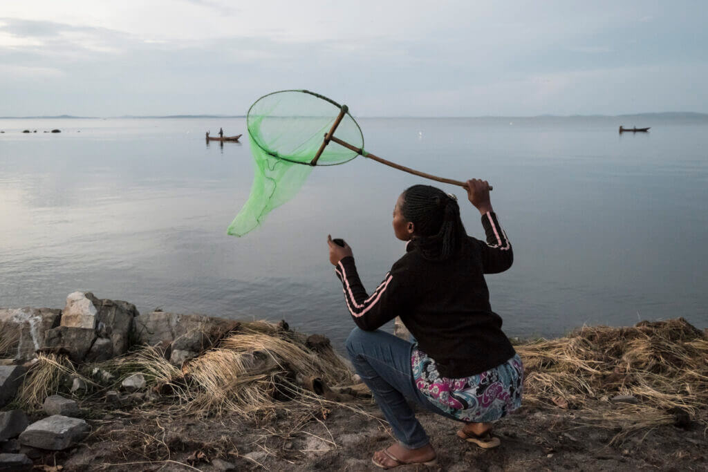 A womanholds a net and holds it above a lake for swarming purposes.