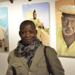 Photograph of Warren Saré in front of a wall displaying three different photos