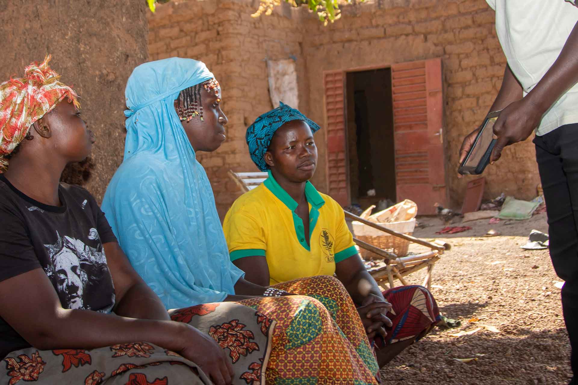 A group of women engage with a Target Malaria staff member in Burkina Faso.