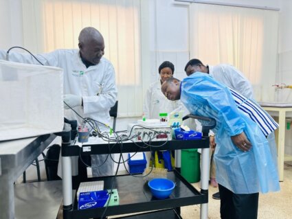 Prof. Abdoulaye Diabaté, a pair of Target Malaria scientists and the Minister examine lab equiptment
