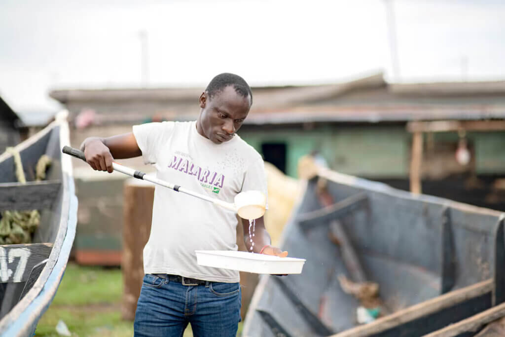 A target malaria employee holds a tray of water